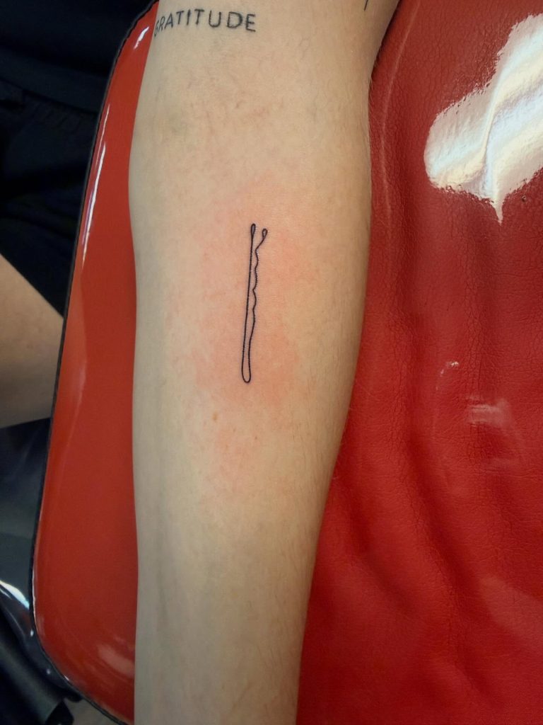 Fine line tattoo of a bobby pin.