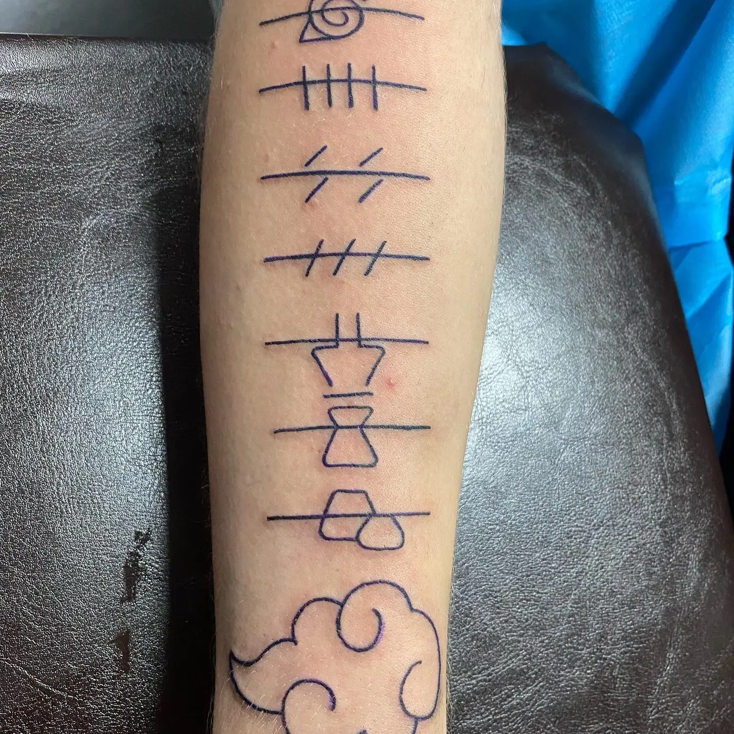 Eight minimalist and fine line tattoos on an arm in black ink.