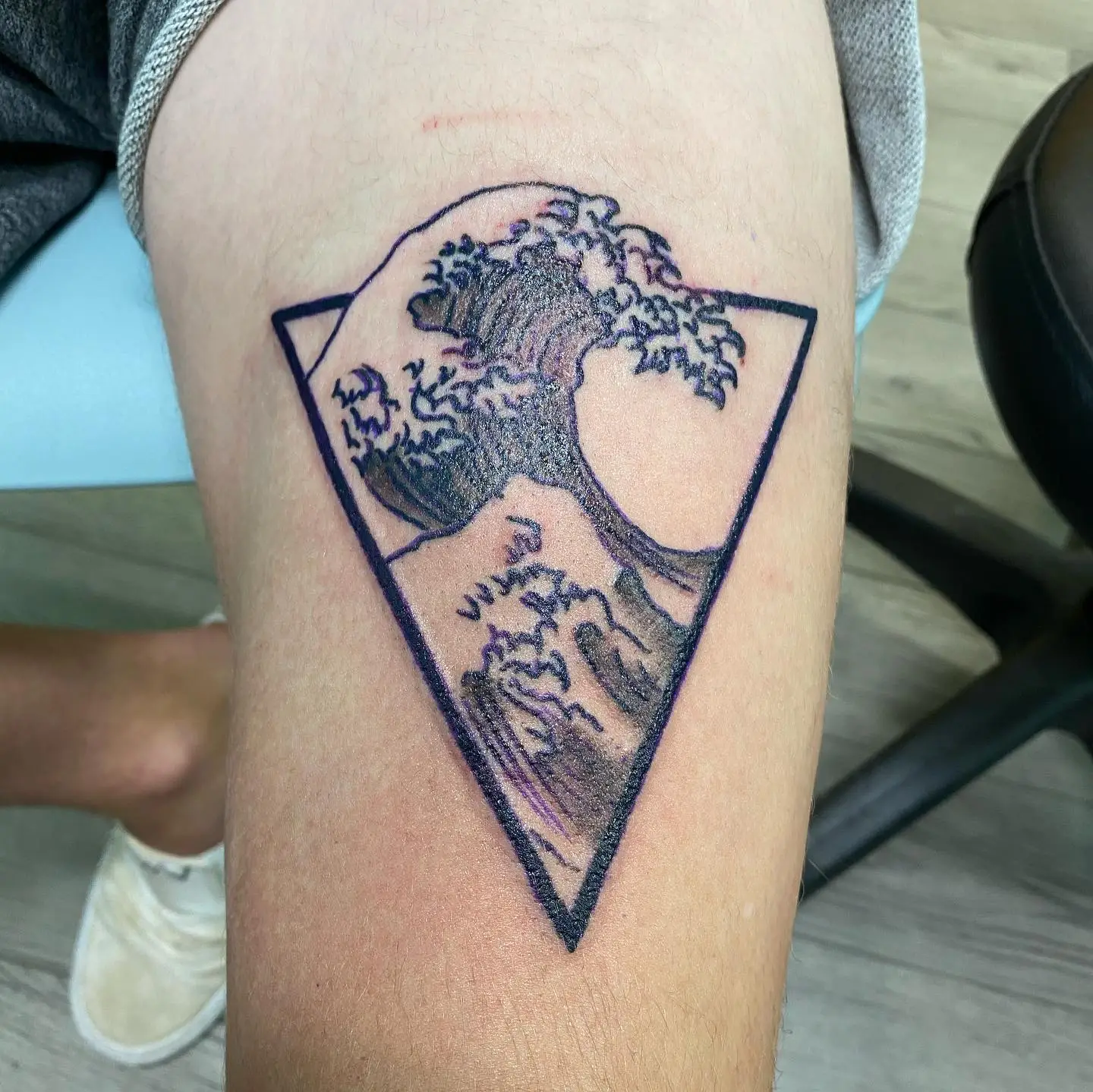 Hokusai wave tattoo inside of a triangle border.