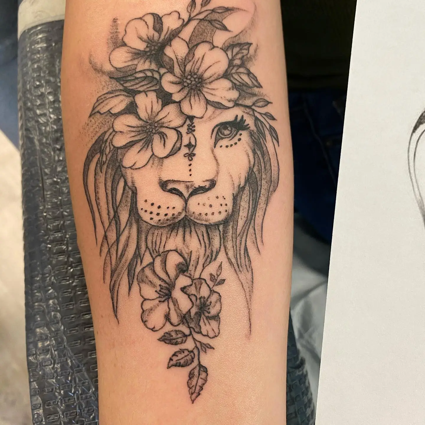 Abstract nature tattoo of a male lions head with flowers as part of the mane.